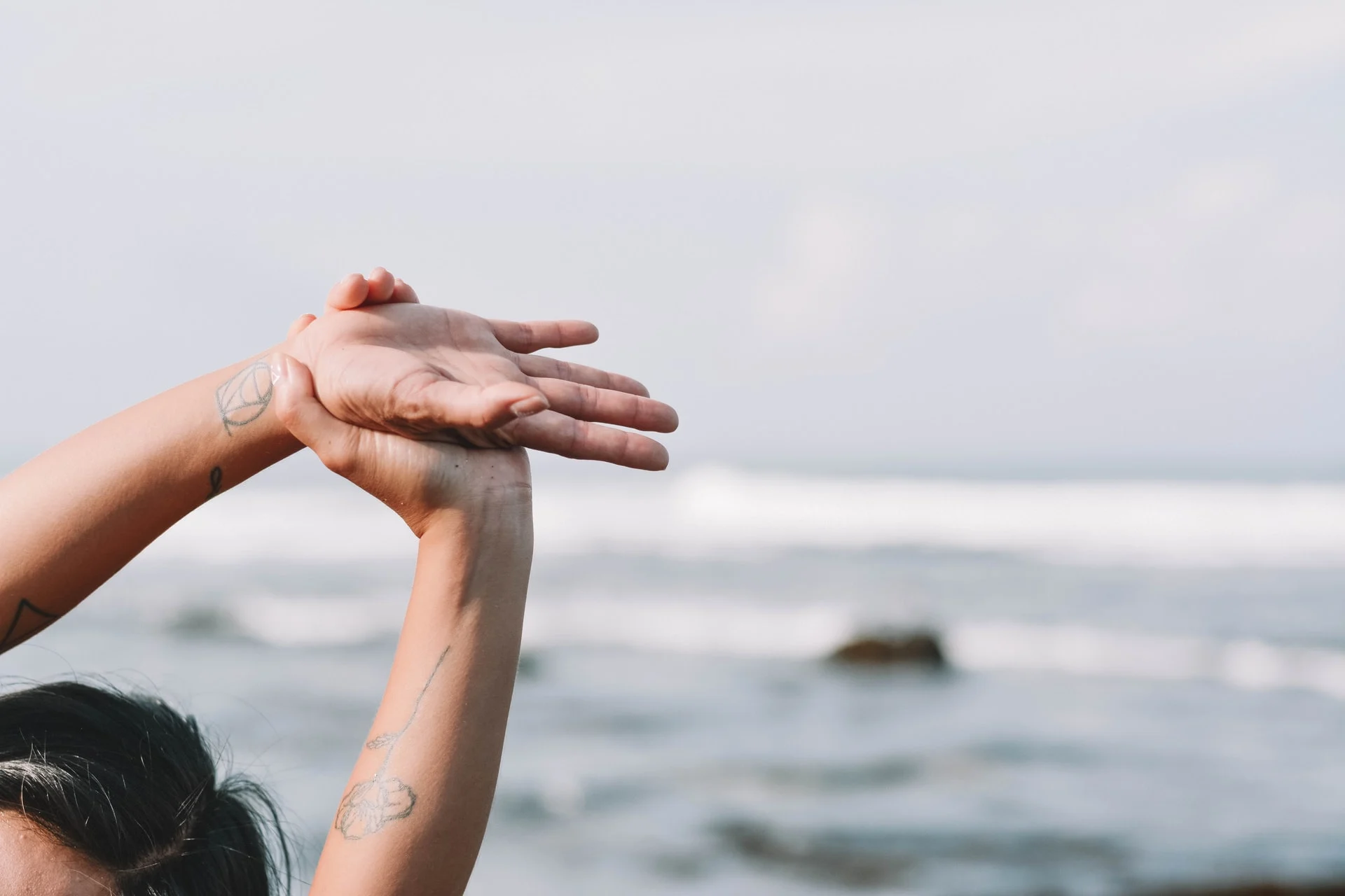 woman doing yoga side stretch on beach as part of her spiritual wellness journey